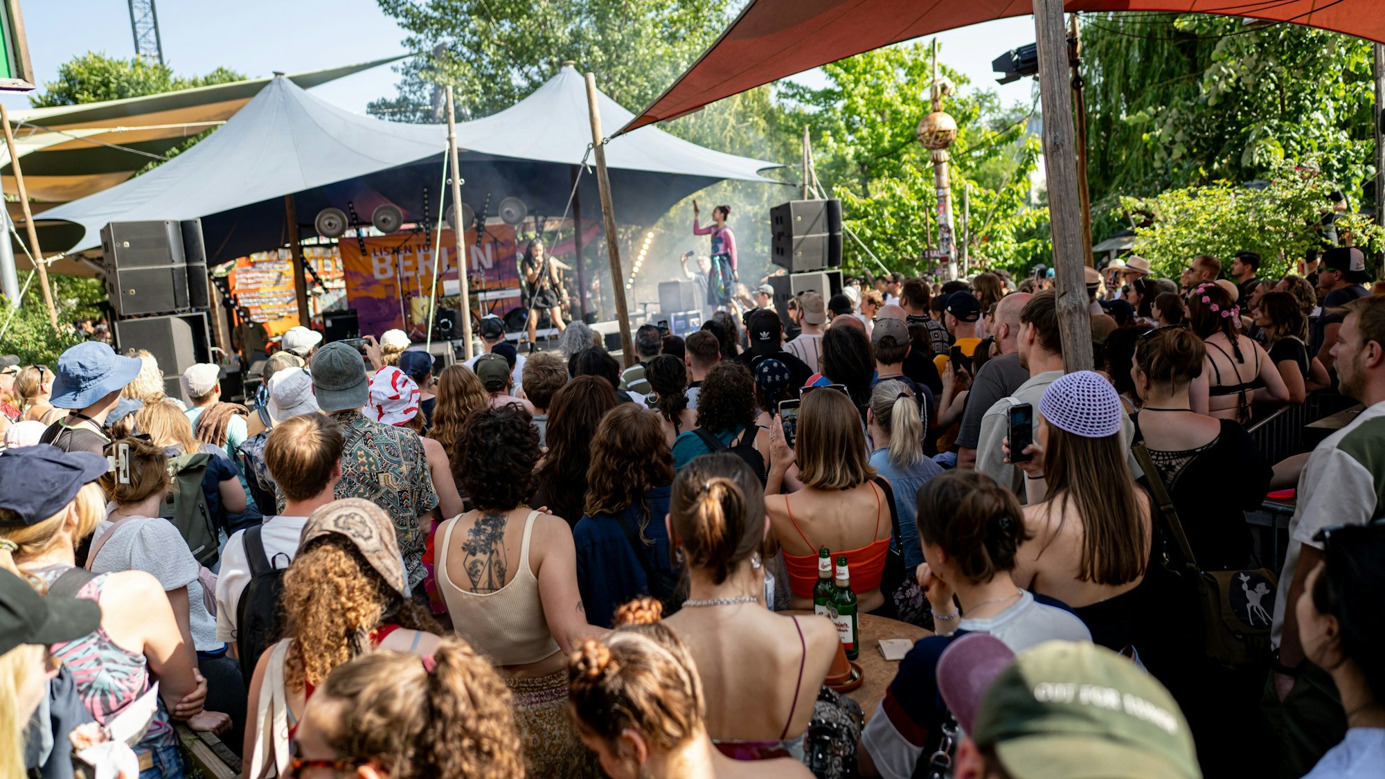 Menschen hören bei der Fête de la Musique am Holzmarkt der Künstlerin Gotopo zu.