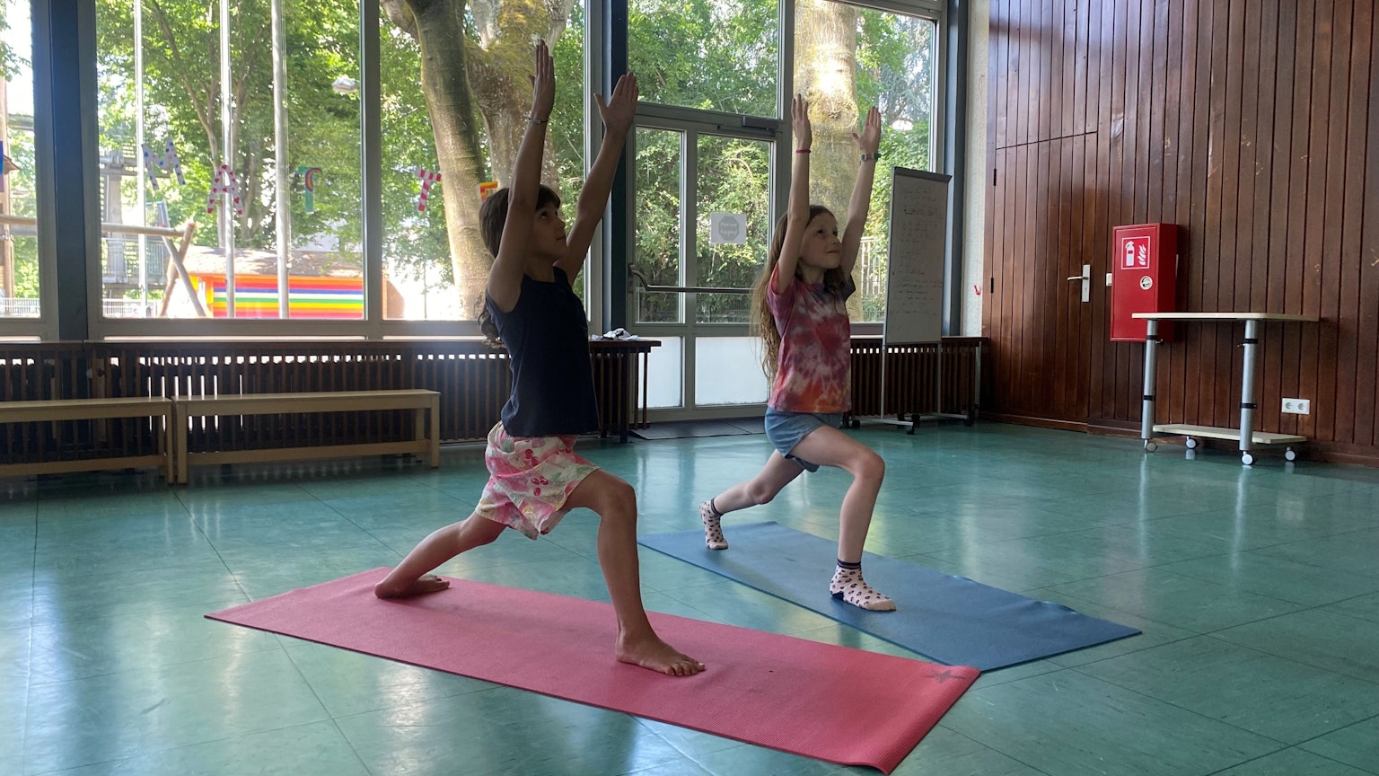 Kinder machen Yoga in der Schule auf einer Matte.
