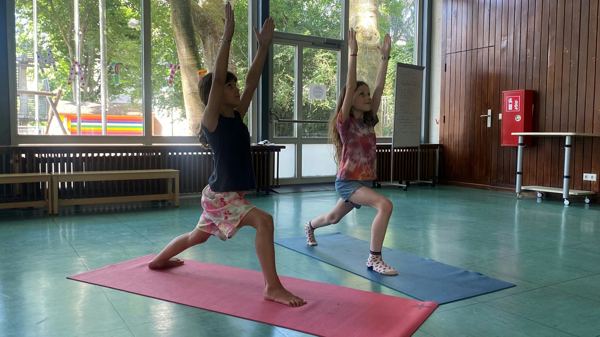Kinder machen Yoga in der Schule auf einer Matte.