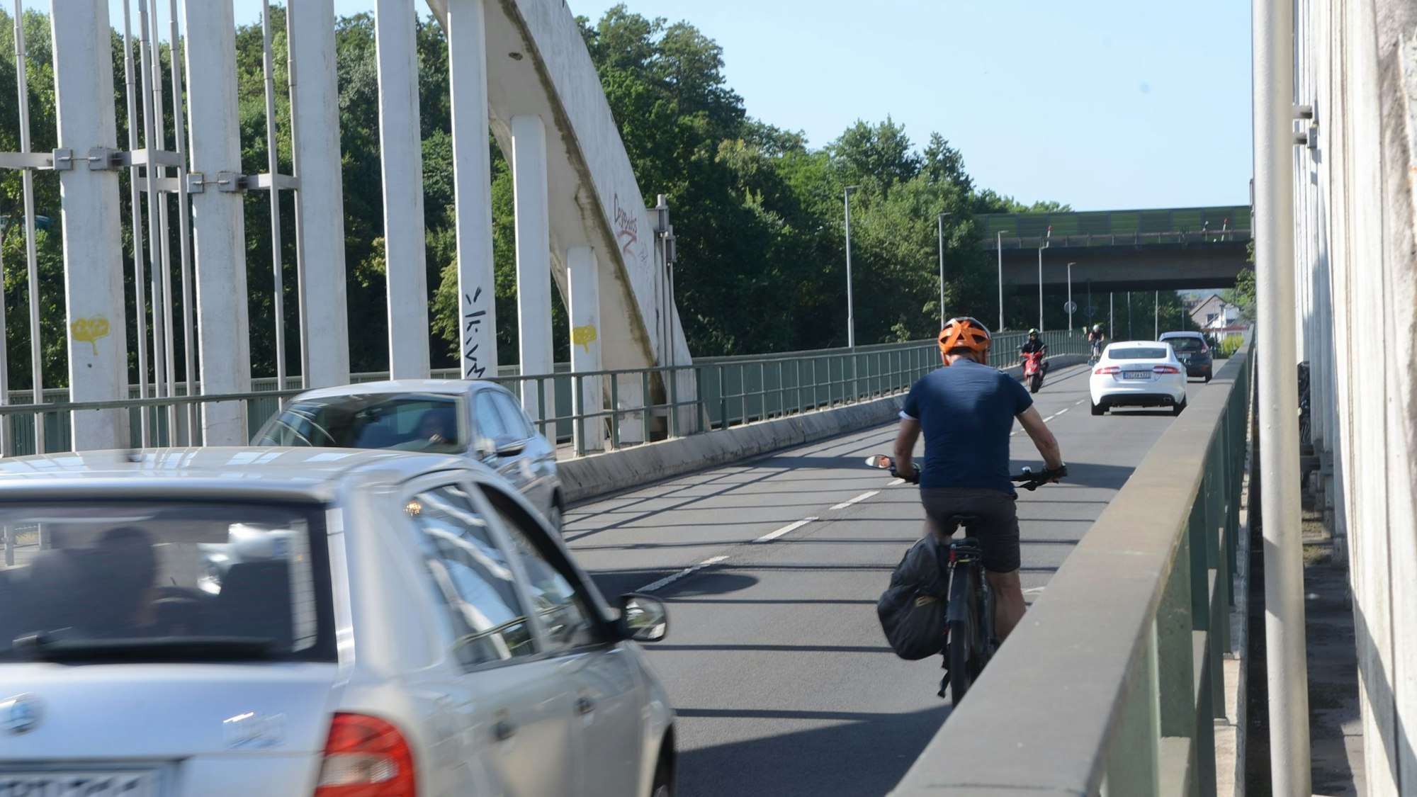 Ein Radfahrer und mehrere Autos auf einer Brücke.