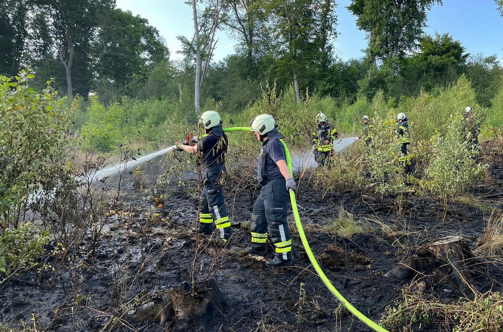 Einsatzkräfte bekämpfen nach dem Waldbrand noch Glutnester.