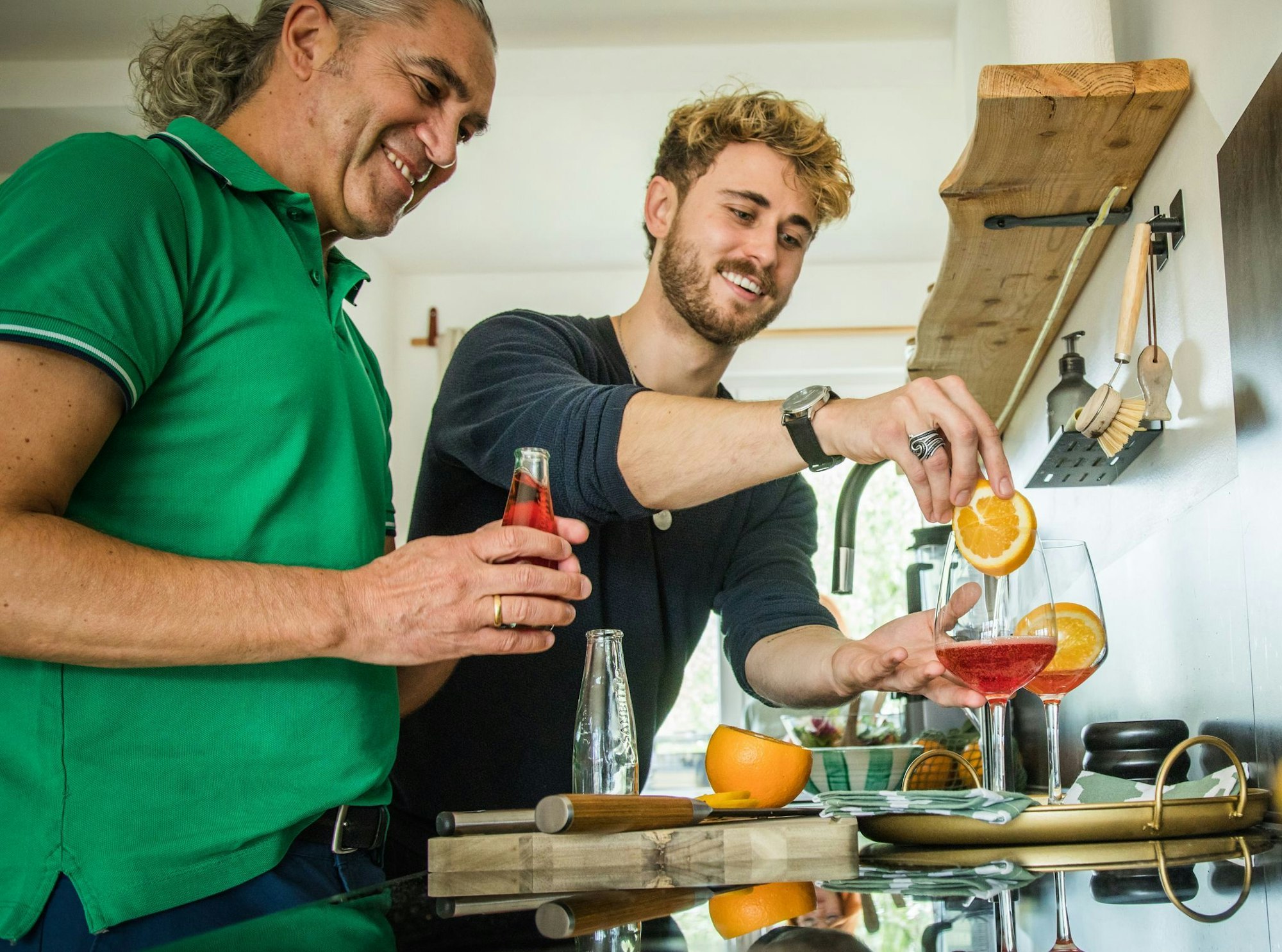 Freude am Experimentieren: Freunde bereiten in der heimischen Küche einen alkoholfreien Aperitif mit Sanbitter zu. Er ist für seine rote Farbe und bittersüße, herbe Geschmacksnote bekannt.