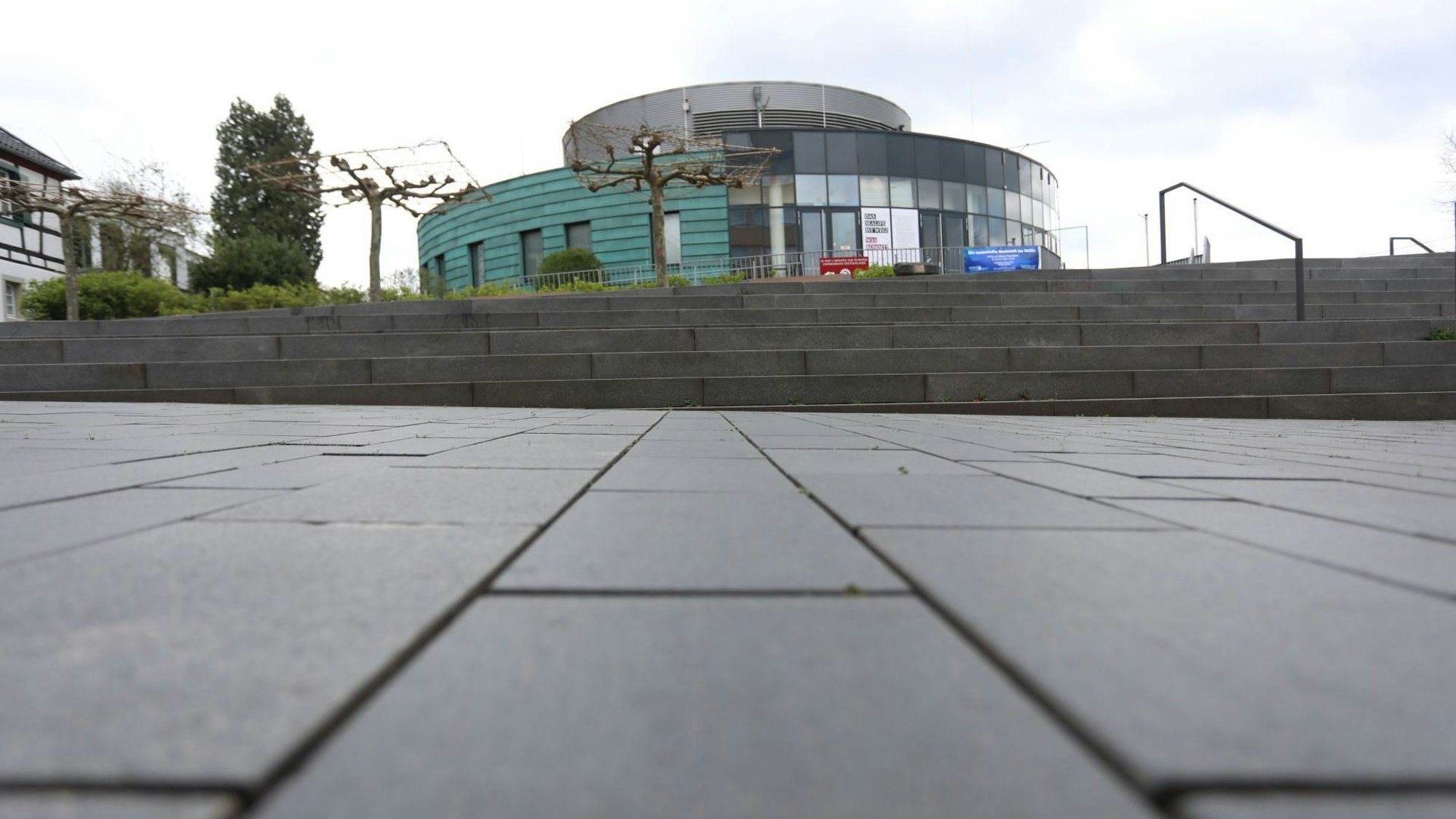 Ein Vorplatz und Treppenstufen vor einem ovalen Gebäude.