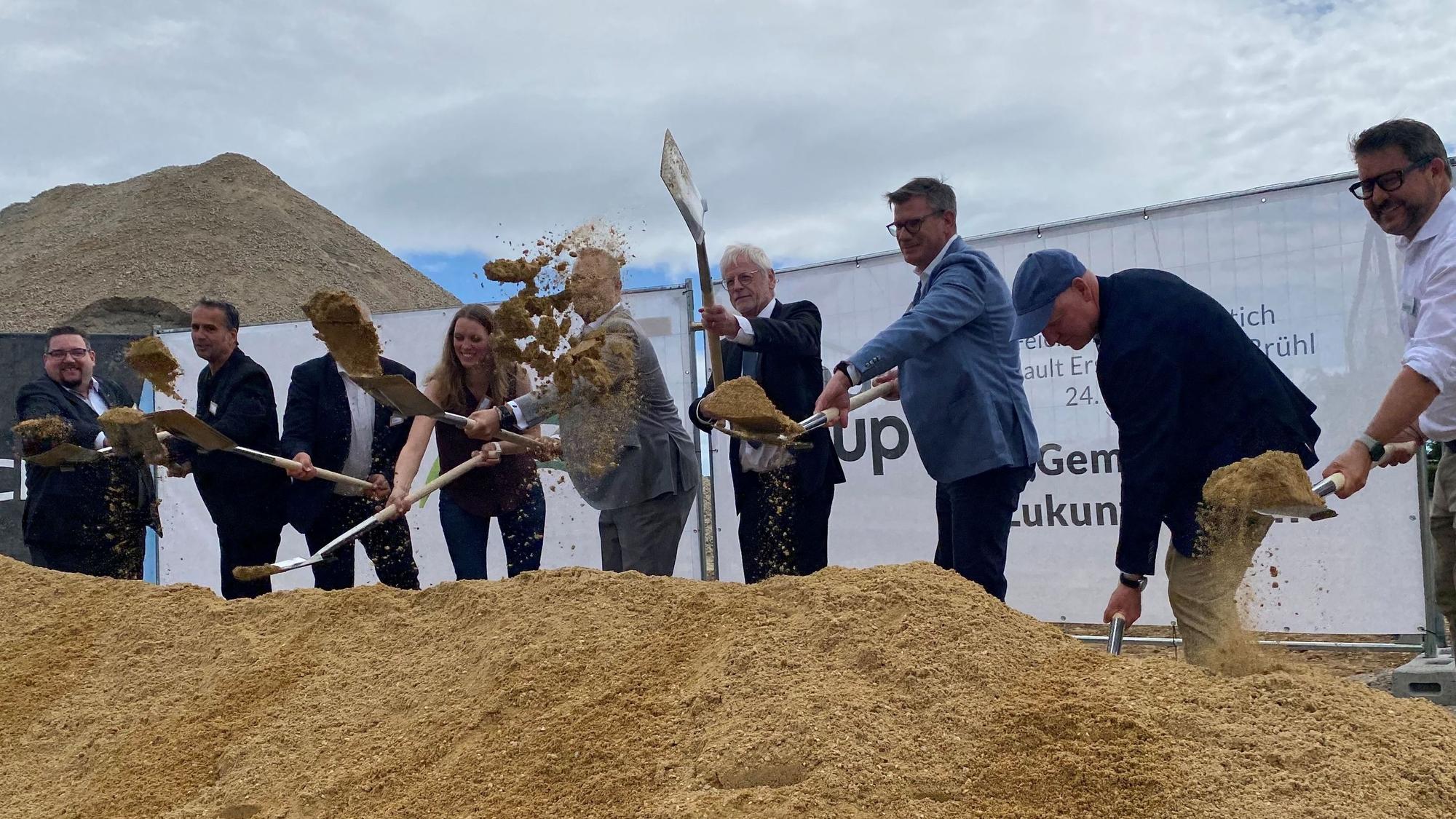 Zu sehen sind Männer und eine Frau, die mit Spaten Sand schaufeln.