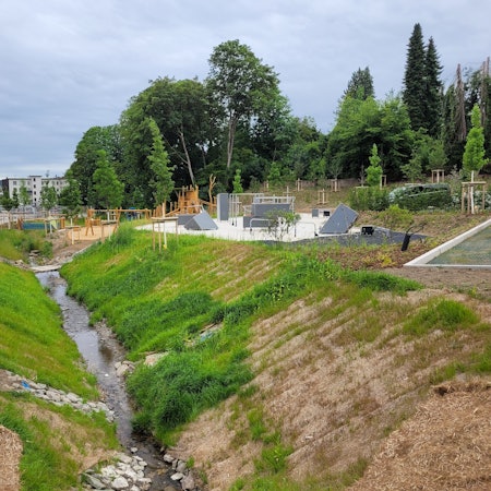 Freifließender Waldbrölbach, Parkour-Gelände (rechts) und Spielplatz: In Waldbröl gedieht auf dem früheren Merkur-Gelände der Grünzug-Ost. Die beiden Bewegungsgelände könnten schon im August freigegeben werden.