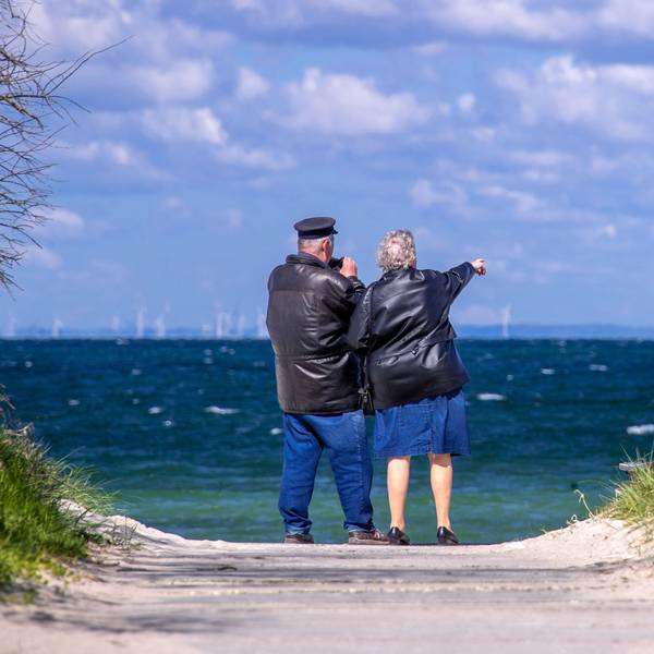 Ein Rentnerpaar steht am ansonsten menschenleeren Strand und schaut aufs Meer. (Archivbild)
