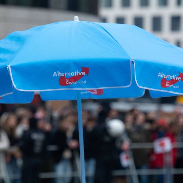Bei einer Veranstaltung in Düsseldorf steht ein blauer AfD-Schirm auf einem Platz.