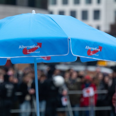 Bei einer Veranstaltung in Düsseldorf steht ein blauer AfD-Schirm auf einem Platz.