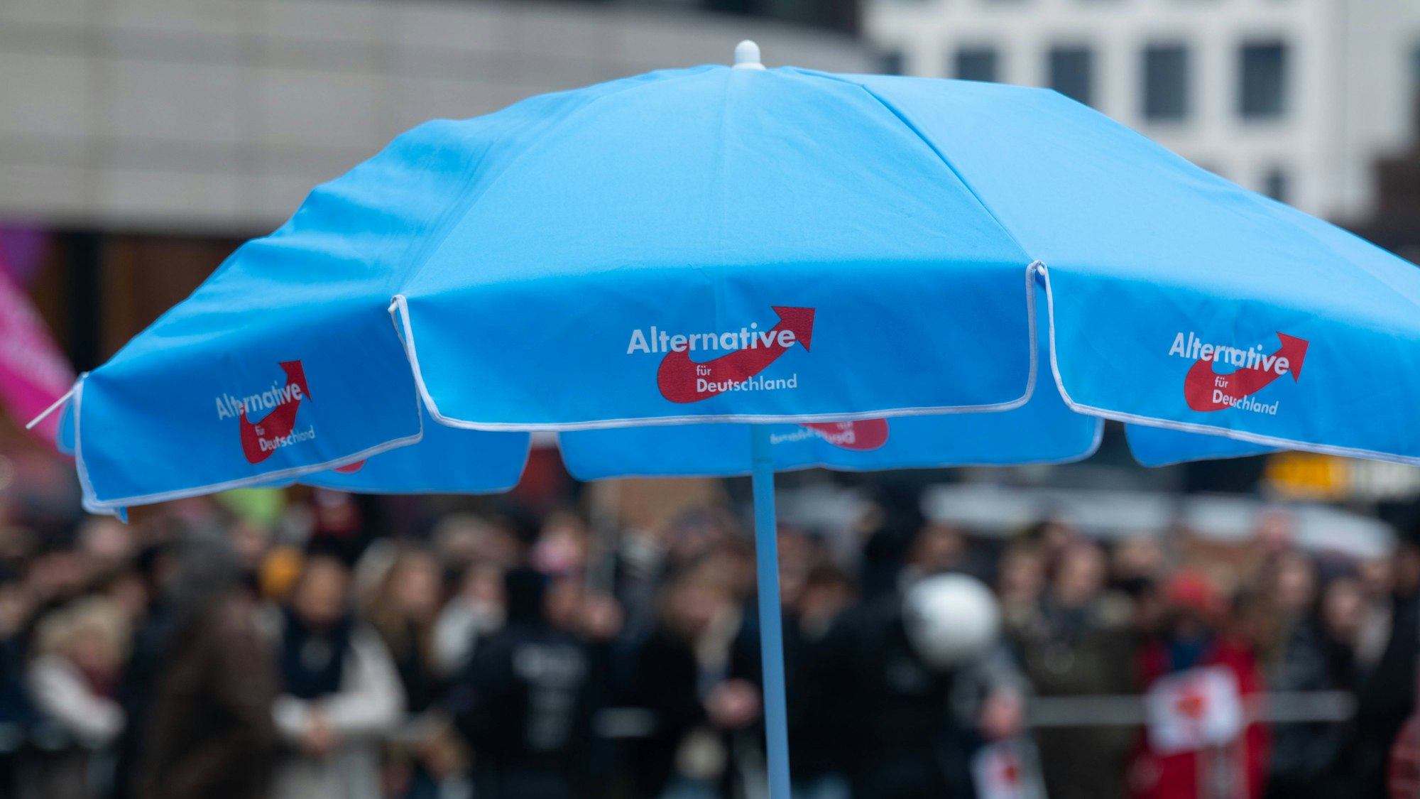 Bei einer Veranstaltung in Düsseldorf steht ein blauer AfD-Schirm auf einem Platz.