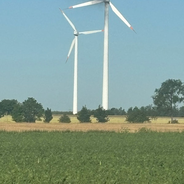 Das Bild zeigt zwei Windkraftanlagen. An einer steigt schwarzer Qualm empor.