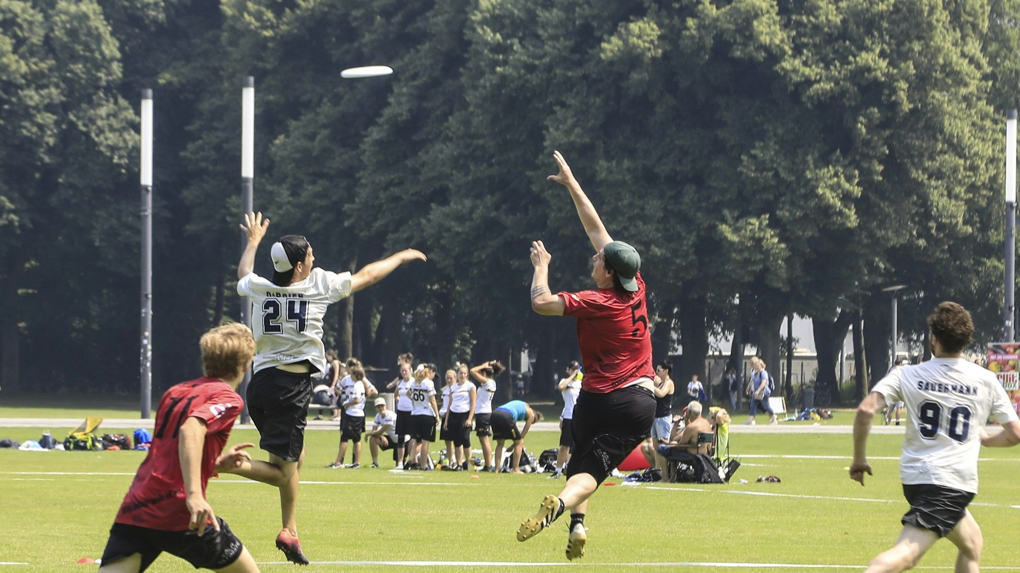 Zu sehen sind mehrere Personen, die einer Frisbee-Scheibe hinterherjagen.