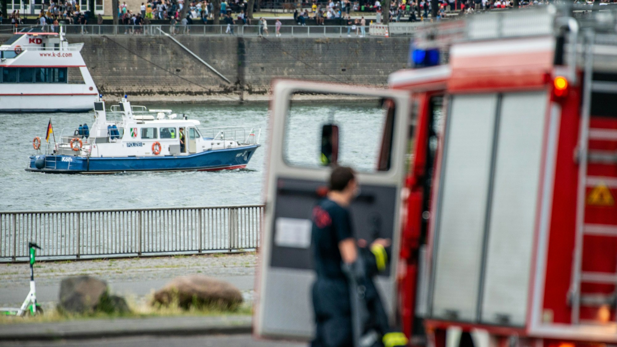 Ein Polizeiboot auf dem Rhein und ein Einsatzwagen der Feuerwehr am Ufer (Symbolfoto).