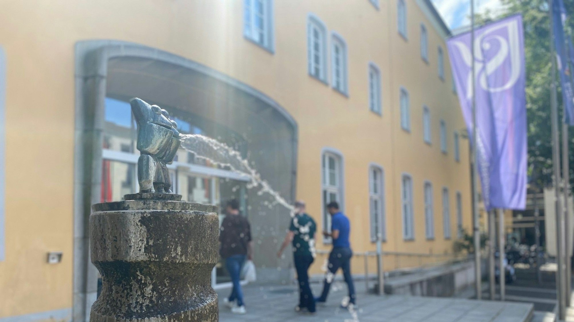 Zu sehen ist ein Brunnen und im Hintergrund der Eingang des Ratshauses.