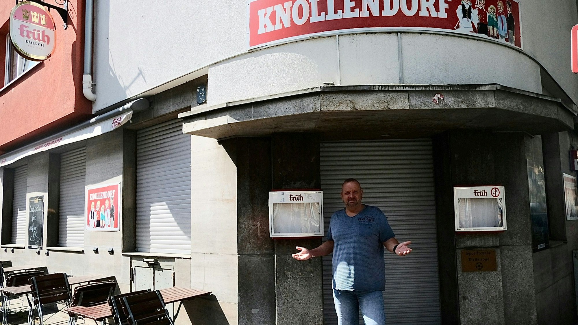 Ein Mann steht mit gehobenem Armen vor der geschlossenen Eingangstür seines Lokals Knollendorf.