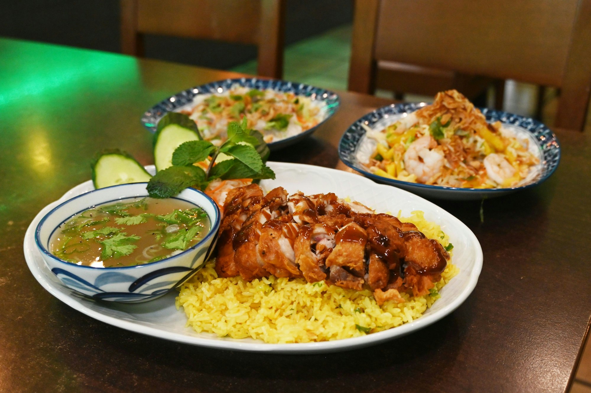 Tellergericht mit gelbgoldenem Reis und Sauce sowie ein Geflügelsalat in einem extra Schälchen ist zu sehen.