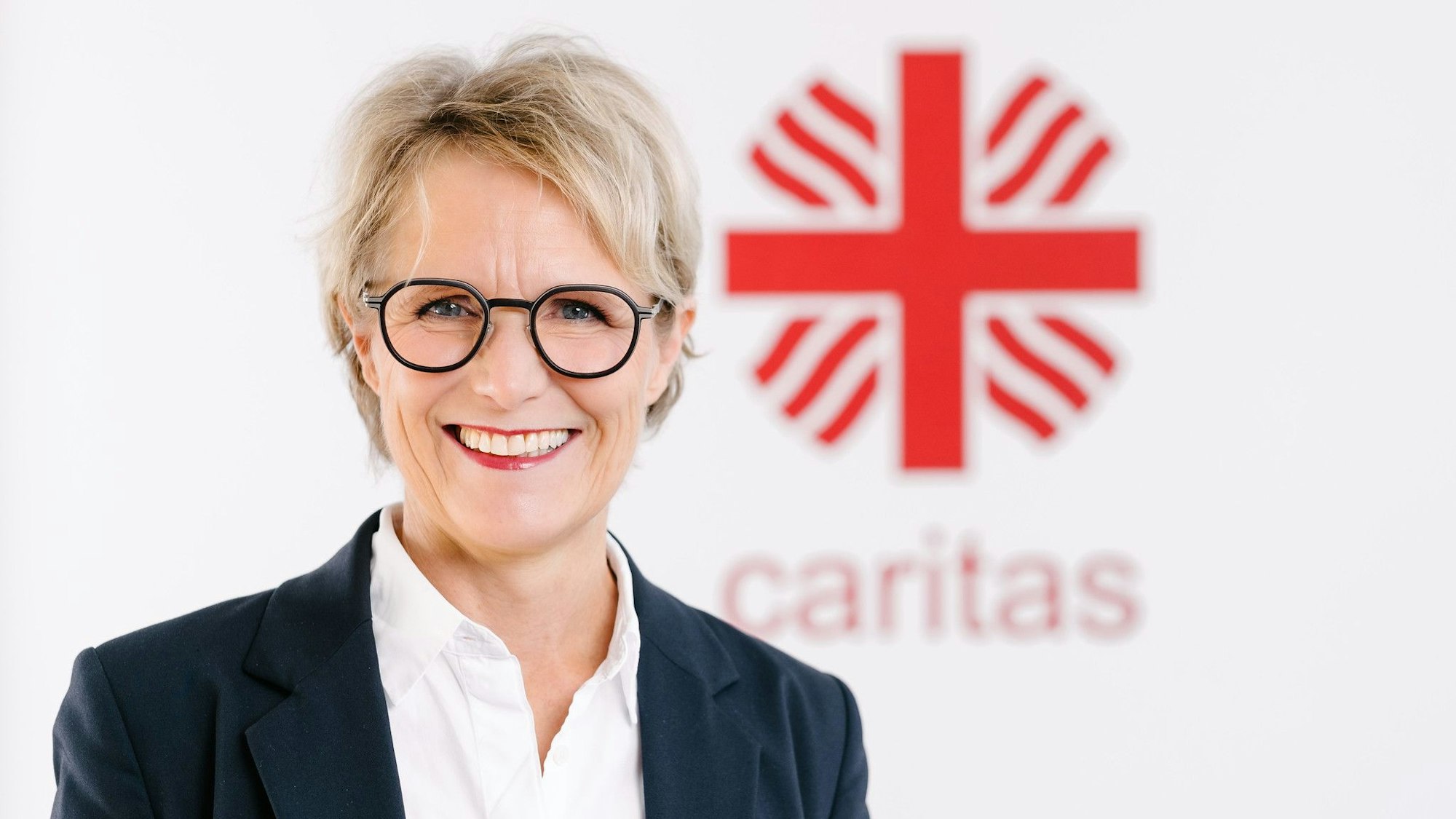 Das Foto zeigt die Finanzvorständin vor dem Caritas-Logo.