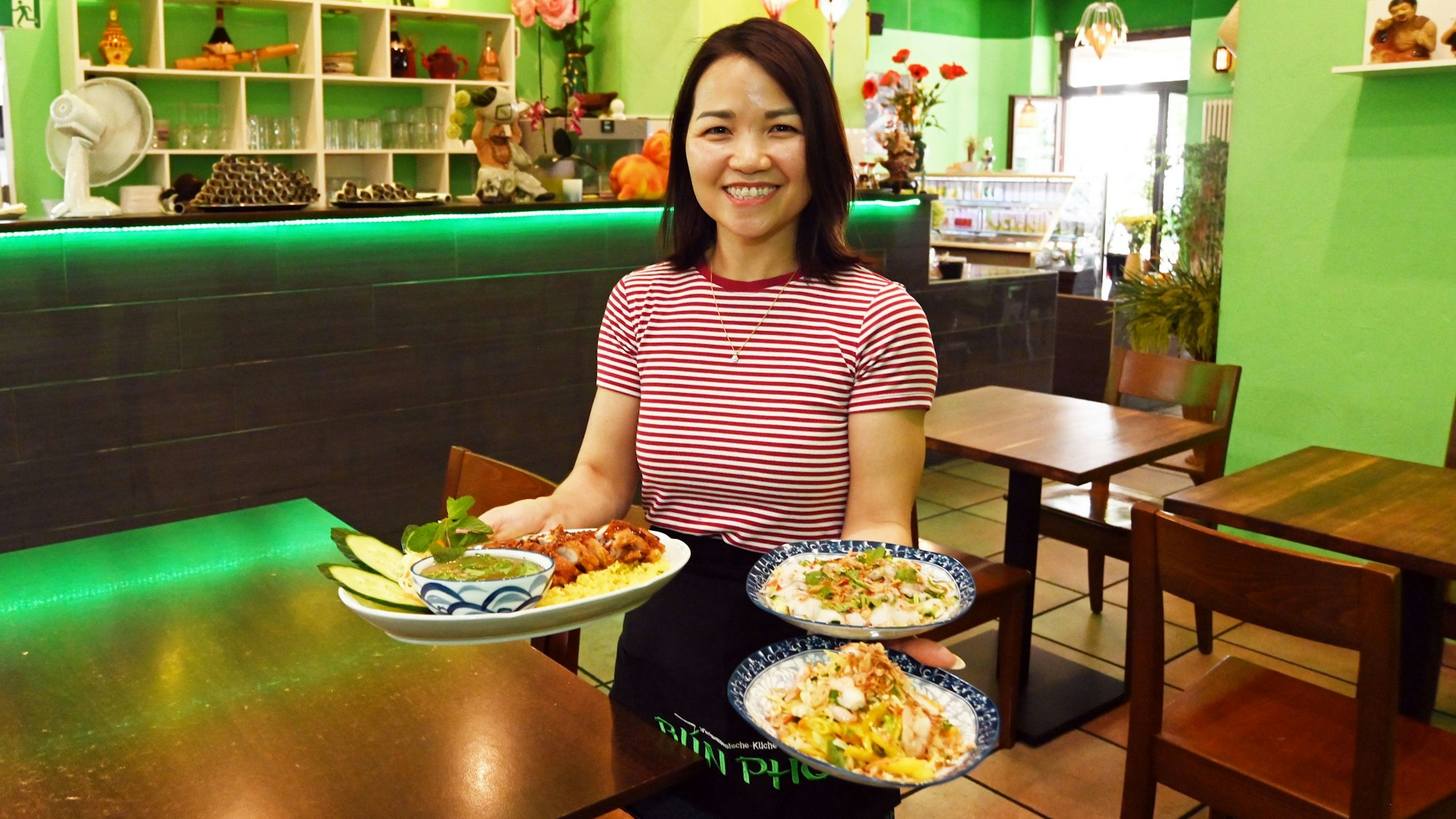 Eine Servicekraft präsentiert im Lokal drei Tellergerichte.