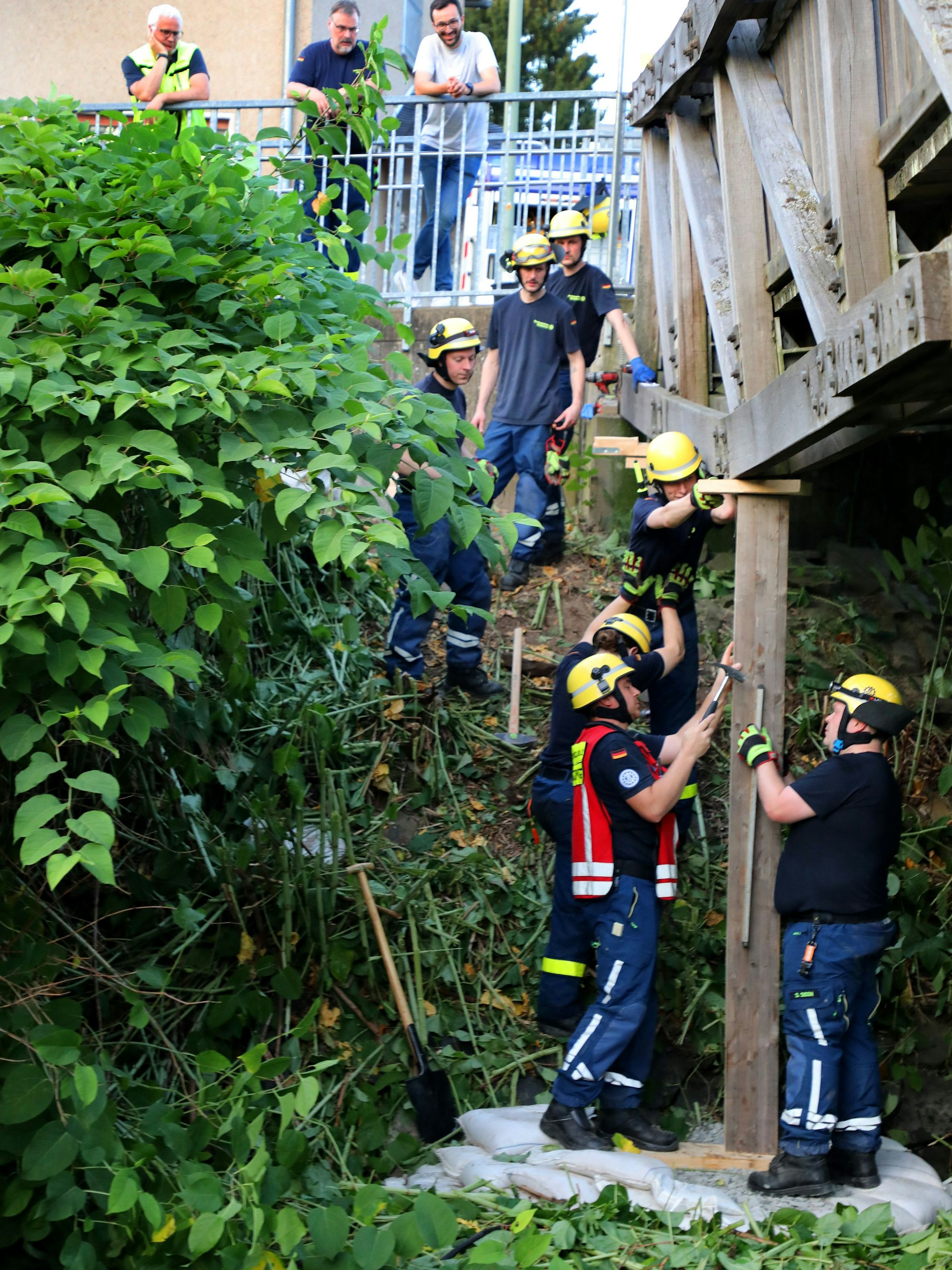 THW-Helfer sichern mit Holzstützen eine bereits angebrochene Holzkonstruktion der Brücke über die Sülz.