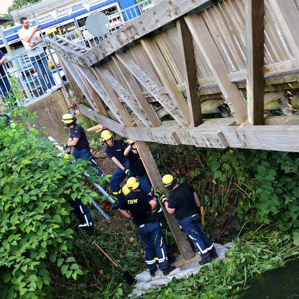 THW-Helfer stützen eine einsturzgefährdete Brücke mit einem Holzbalken ab.