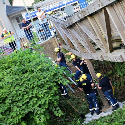 THW-Helfer stützen eine einsturzgefährdete Brücke mit einem Holzbalken ab.
