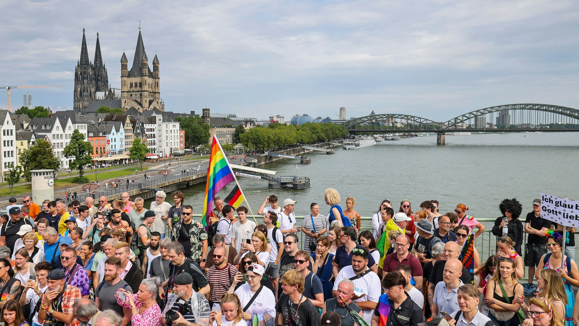 Nordrhein-Westfalen, Köln: Eine Regenbogenflagge bei den Zuschauern beim CSD in Köln, im Hintergrund der Kölner Dom. (Archivbild 2024)