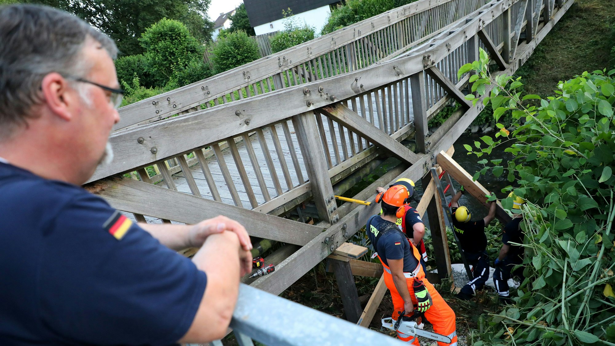 THW-Ortsbeauftragter Stephan Menrath steht am Geländer einer Brückenzufahrt und beobachtet einen THW-Einsatz.