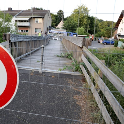 Ein Schild „Durchgang für Fußgänger verboten“ hängt an einem Bauzaun vor einer maroden Holzbrücke in Rösrath.