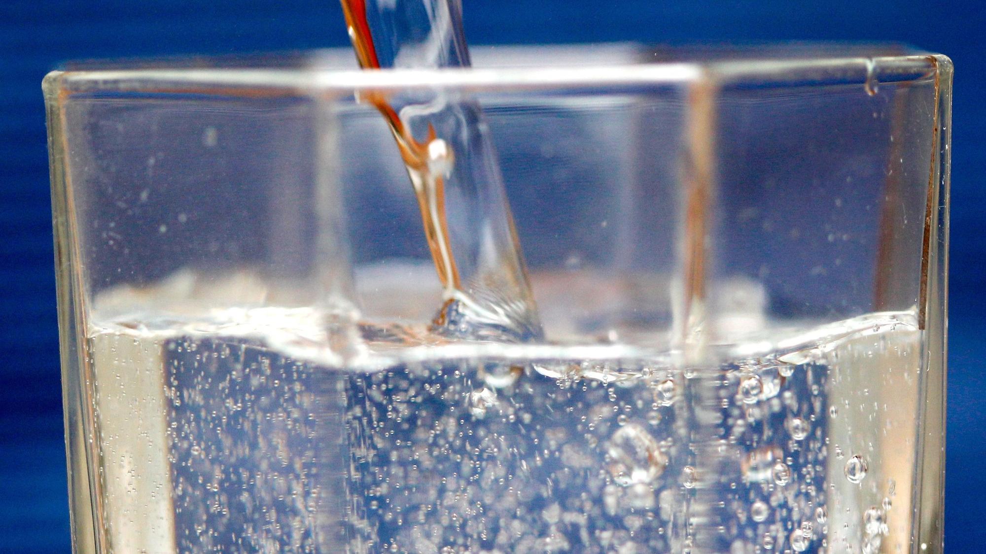 Sprudelwasser wird in ein Glas geschüttet.