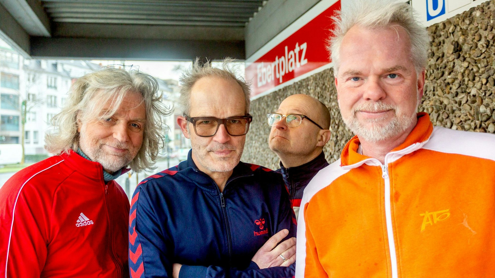 Die vier Mitglieder der Band Erdmöbel stehen in Trainingsanzügen an der Kölner Haltestelle Ebertplatz.
