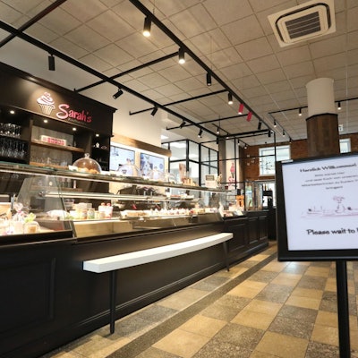 Ein in braun gehaltenes Café´ mit einer langen Kuchen- und Tortentheke.