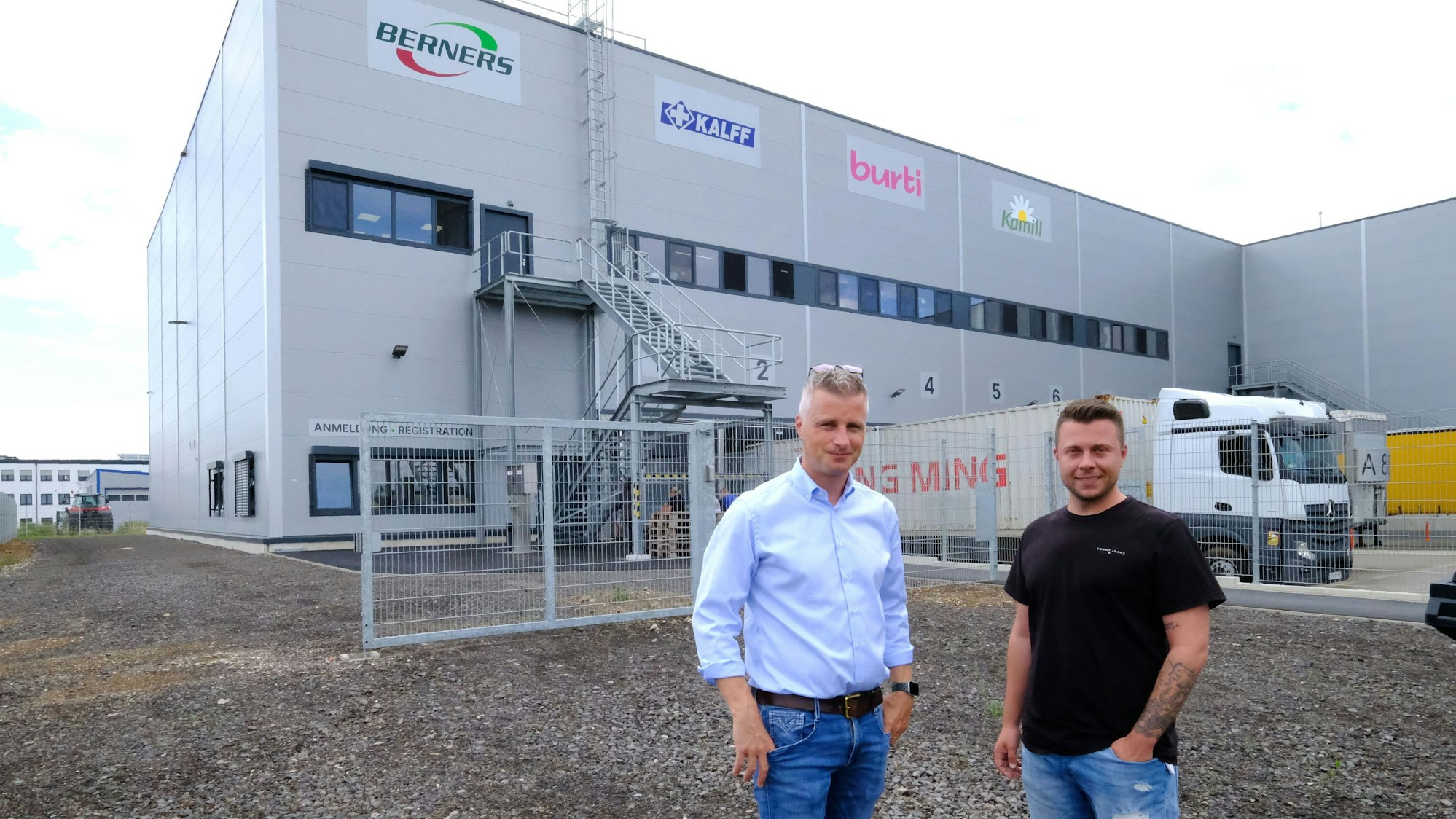 Daniel Claßen und Betriebsleiter Steffen Steinhauer stehen vor einer Logistikhalle in einem Gewerbegebiet.