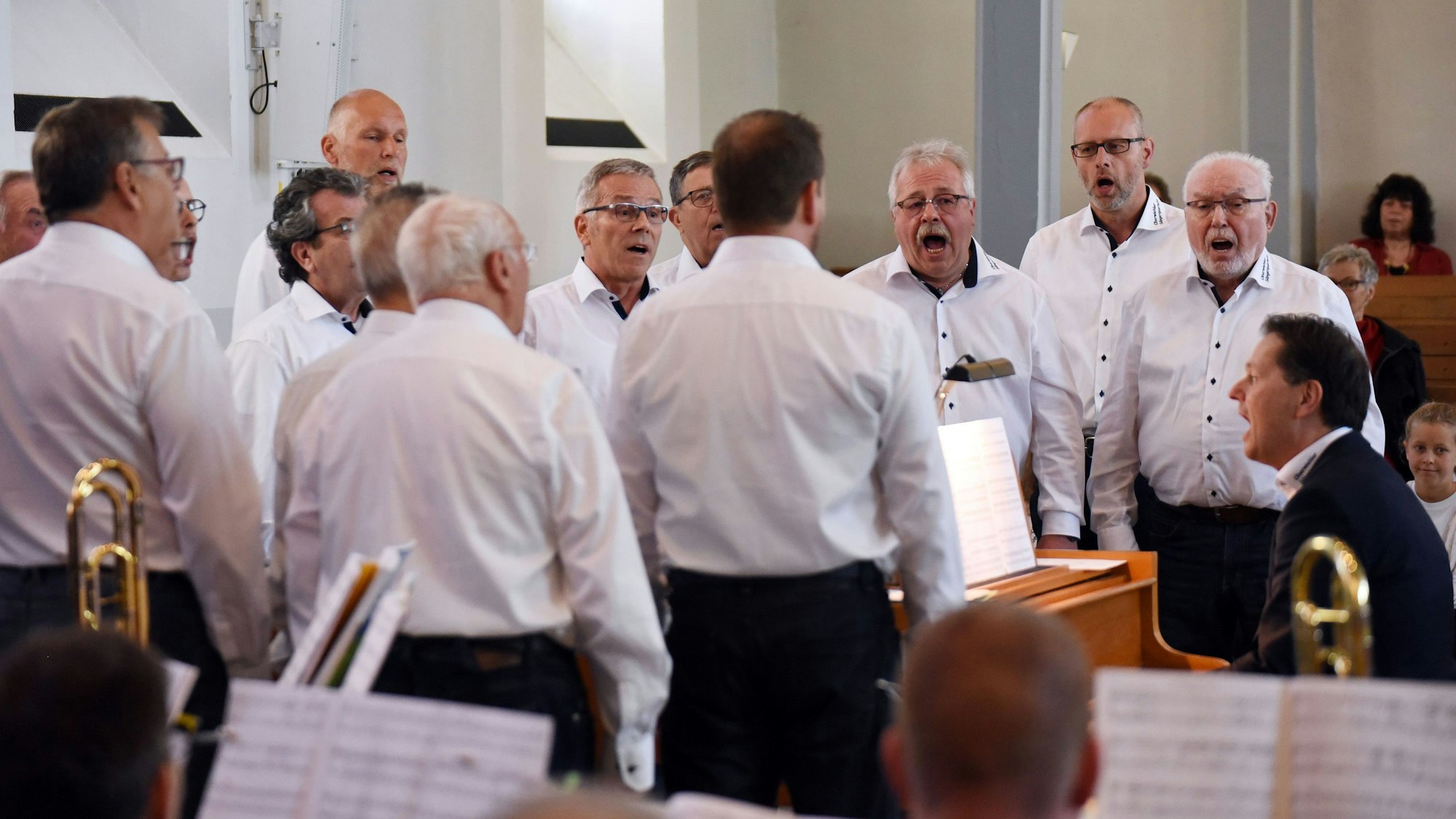 Ein Männerchor singt in weißen Hemden.