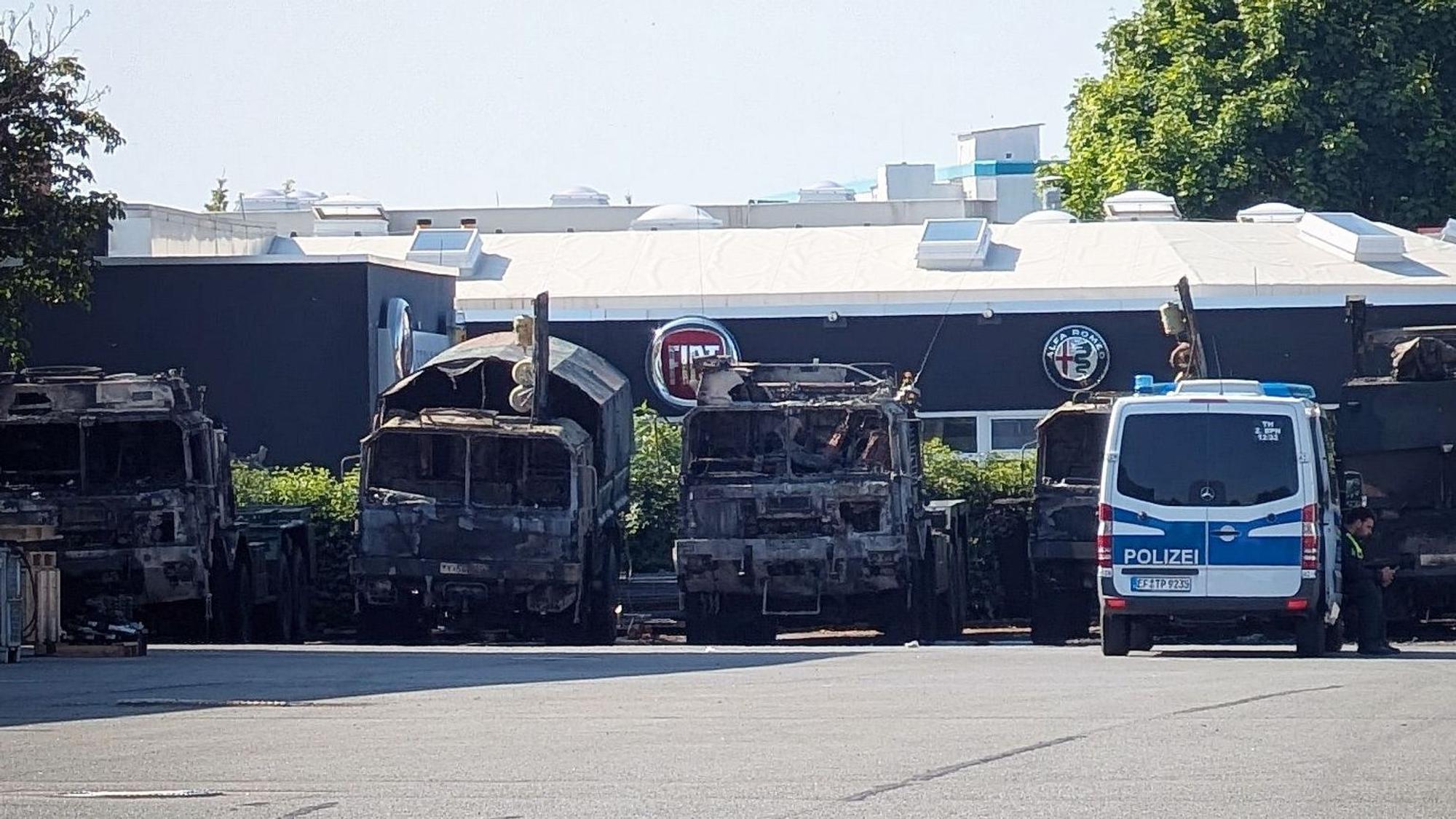 ARCHIV - 22.06.2025, Thüringen, Erfurt: Ein Polizeifahrzeug steht vor mehreren verbrannten Militärlastern auf dem Gelände eines Nutzfahrzeug-Serviceunternehmen. (zu dpa: «Russischsprachiges Video zu Brandanschlag auf Bundeswehr») Foto: Martin Wichmann/WichmannTV/dpa +++ dpa-Bildfunk +++