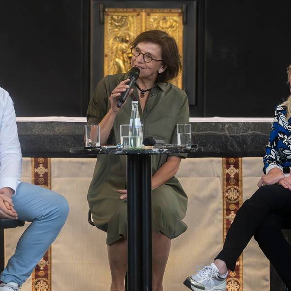 Das Bild zeigt einen Moment der Talkrunde. Marianne Komp hält ein Mikrofon in der Hand, die beiden Landratskandidaten sitzen auf Stühlen und lauschen.