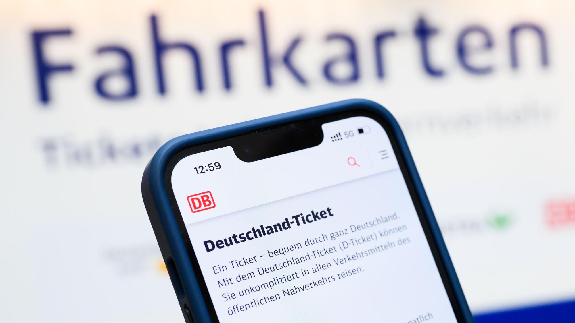 Eine Person hält am Hauptbahnhof ein Smartphone in der Hand, auf dessen Display eine Information zum Kauf des Deutschlandtickets zu sehen ist.