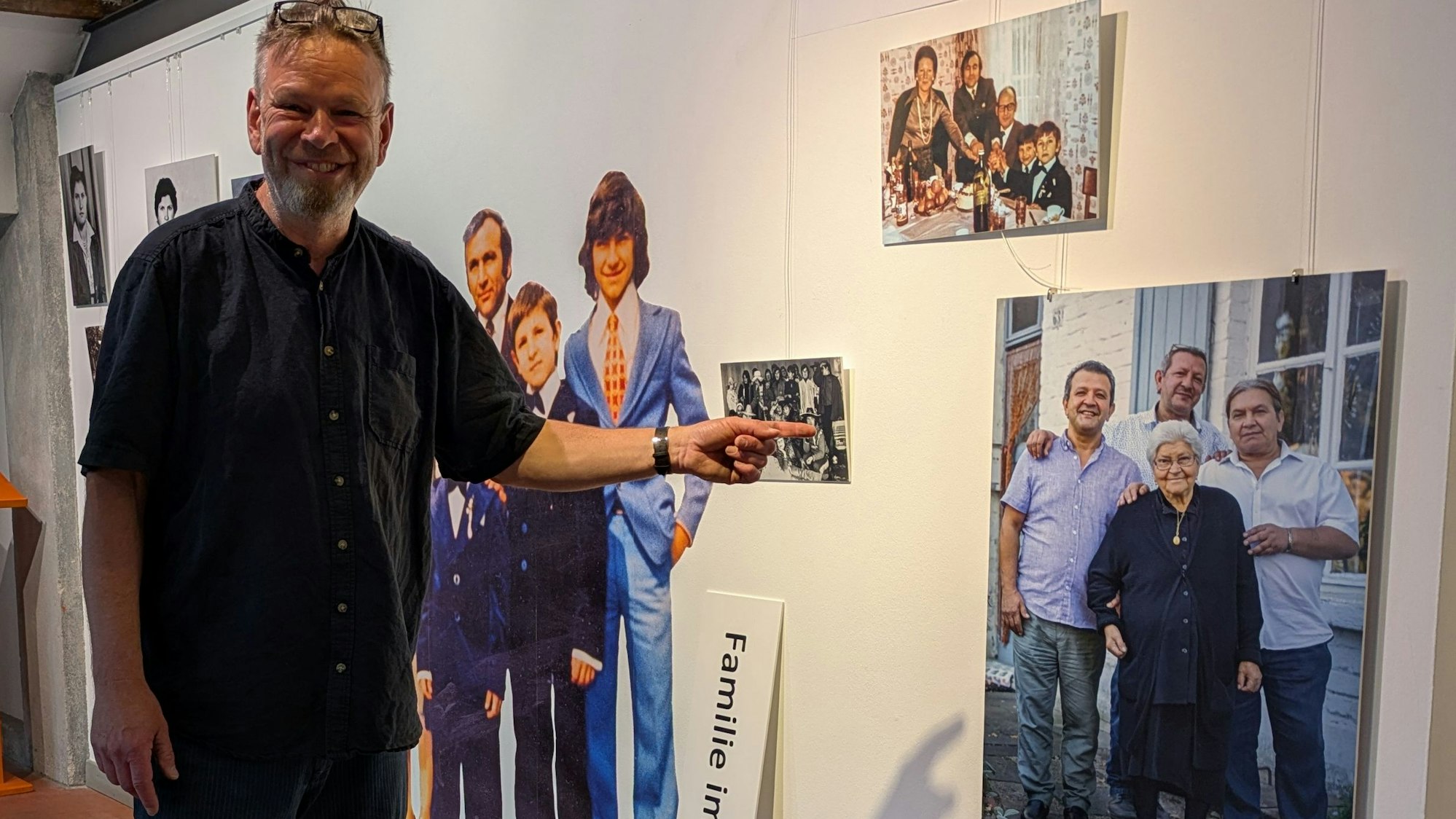Ein Mann zeigt auf ein Foto mit einer alten Frau und drei Männern.