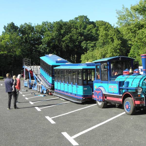Ein türkis-blauer Zug auf Rädern wird in Heimbach-Schwammenauel von einem Autotransporter gefahren.
