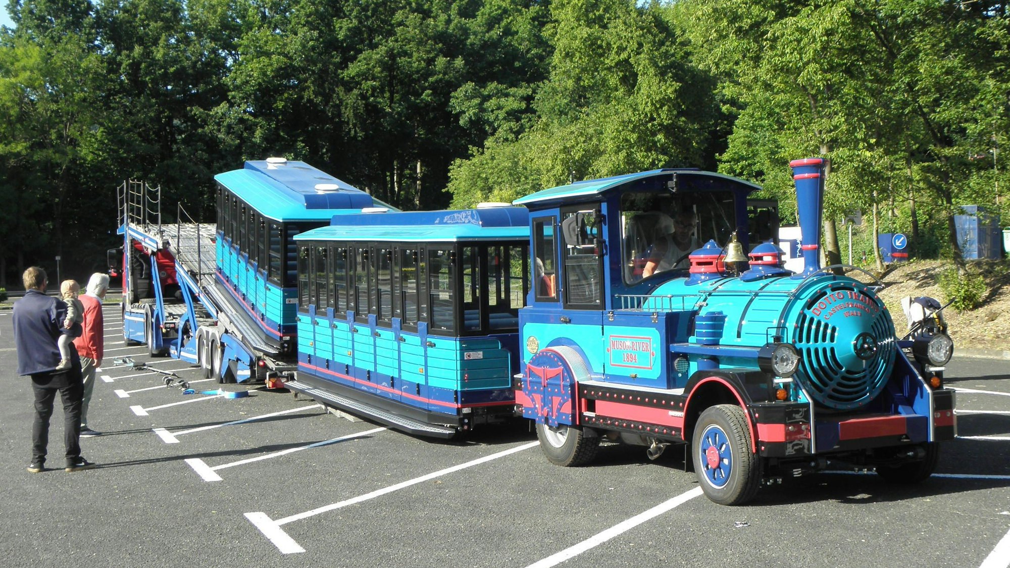 Ein türkis-blauer Zug auf Rädern wird in Heimbach-Schwammenauel von einem Autotransporter gefahren.
