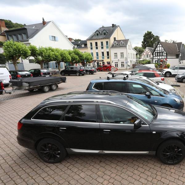 Parkende Fahrzeuge auf einem Platz in einem historischen Ortskern.