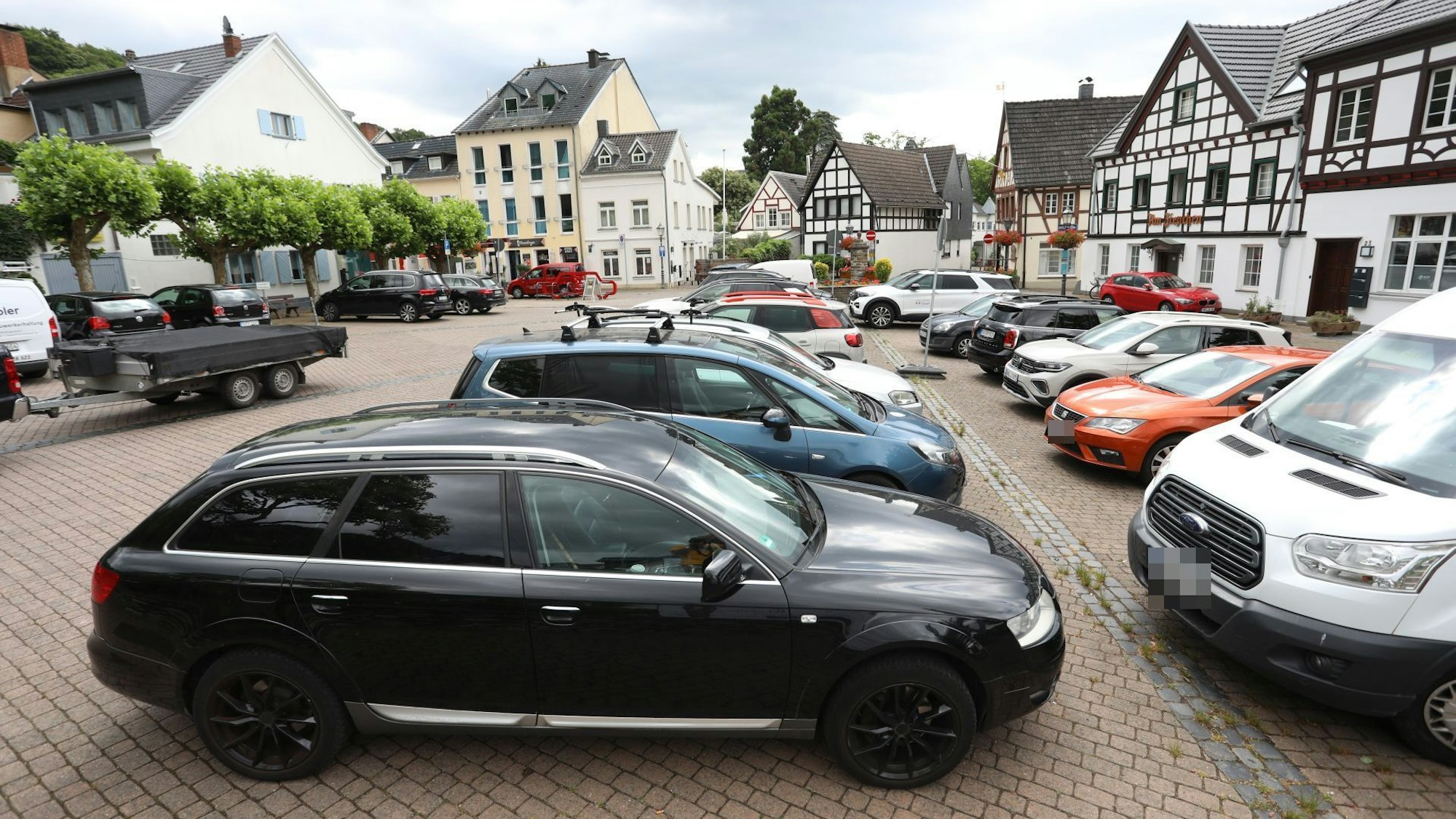 Parkende Fahrzeuge auf einem Platz in einem historischen Ortskern.
