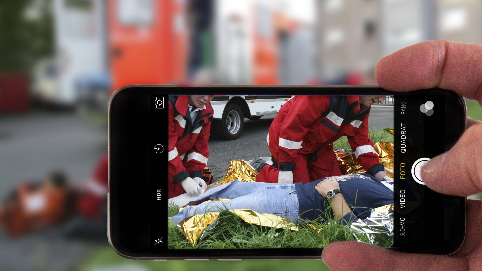 Schaulustige fotografieren bei einem Rettungseinsatz mit der Handykamera. (Symbolfoto)