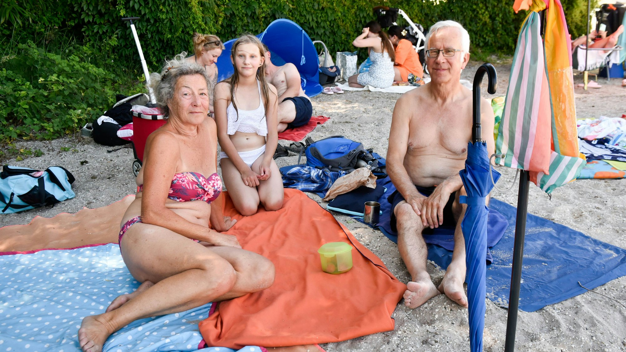 Badegäste sitzen auf Handtüchern.