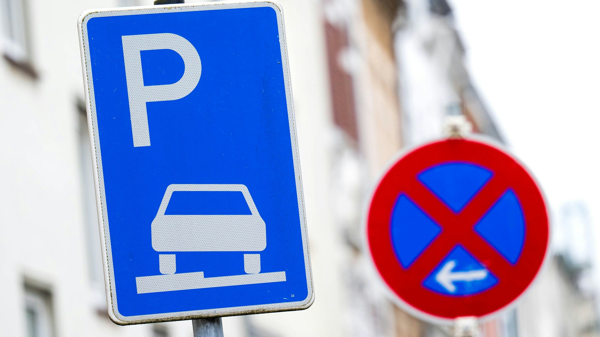 Ein Verkehrszeichen erlaubt das aufgesetzte Parken auf dem Gehweg, daneben steht ein Schild, das ein absolutes Halteverbot anzeigt. Der Parkraum wird in den Innenstädten immer knapper.