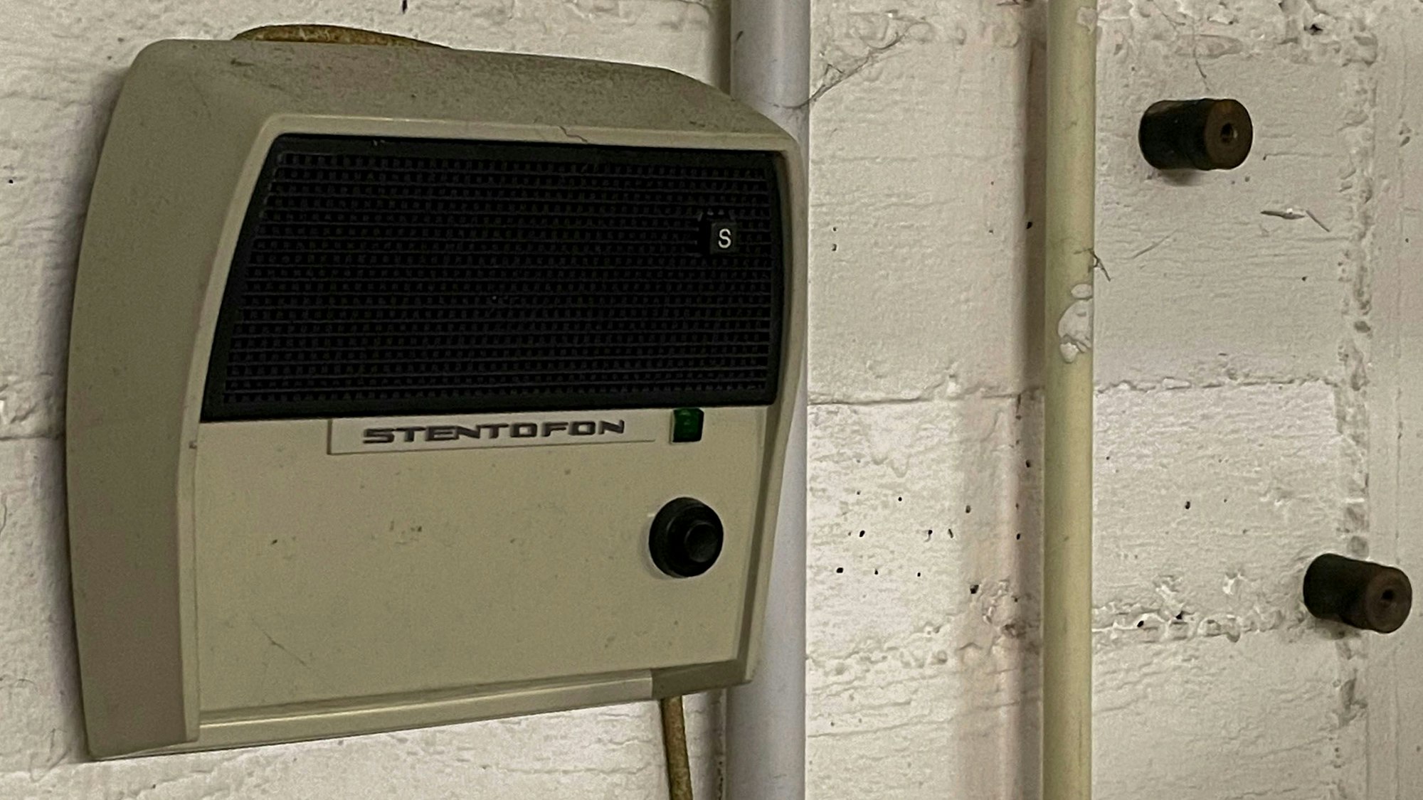 Das Bild zeigt eine alte Lautsprecheranlage, die auf der Betonwand eines Bunkers montiert ist.