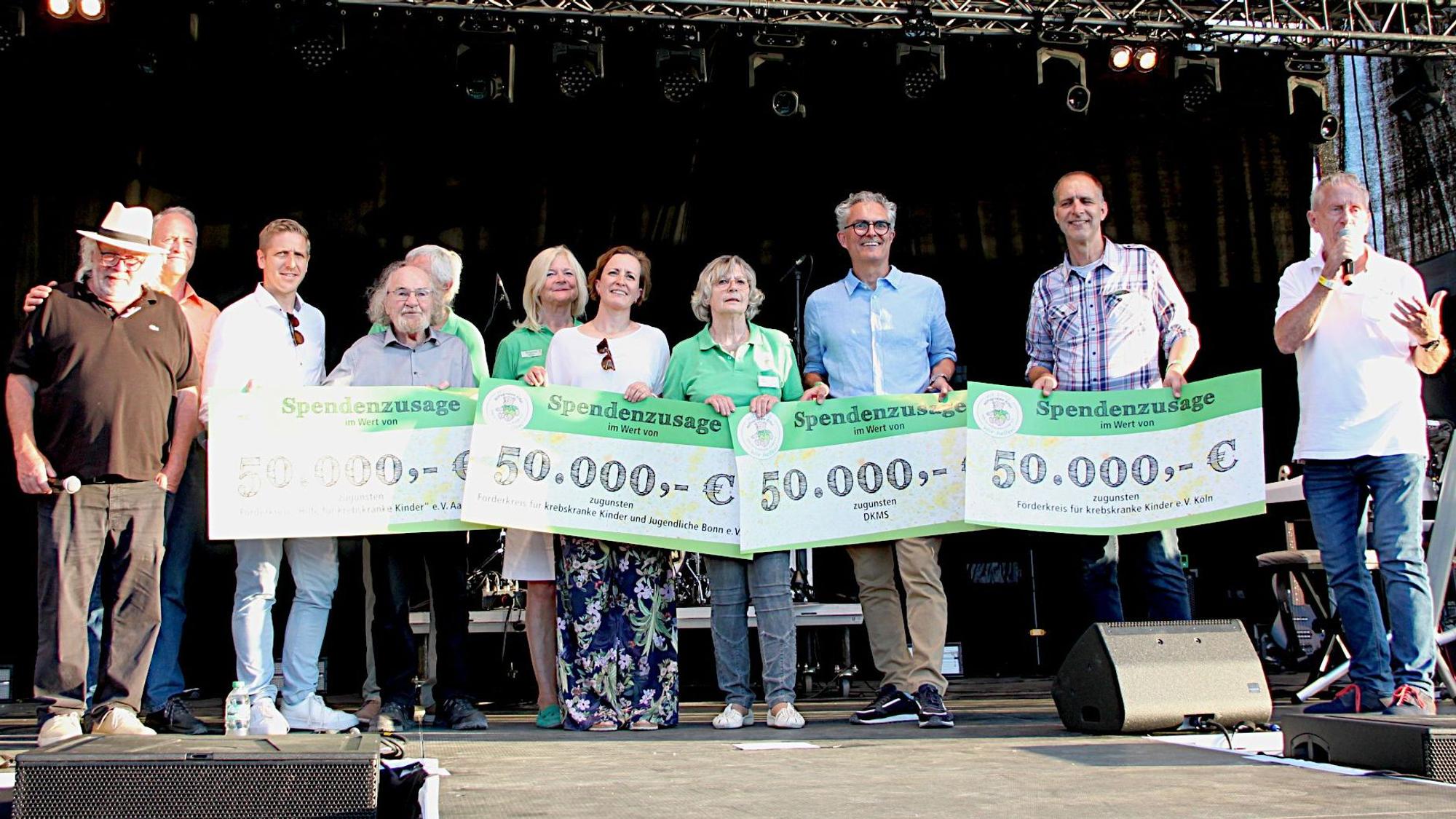 Die Vertreter verschiedener Hilfsorganisationen stehen mit überdimensionierten Spenden-Schecks auf einer Veranstaltungsbühne.