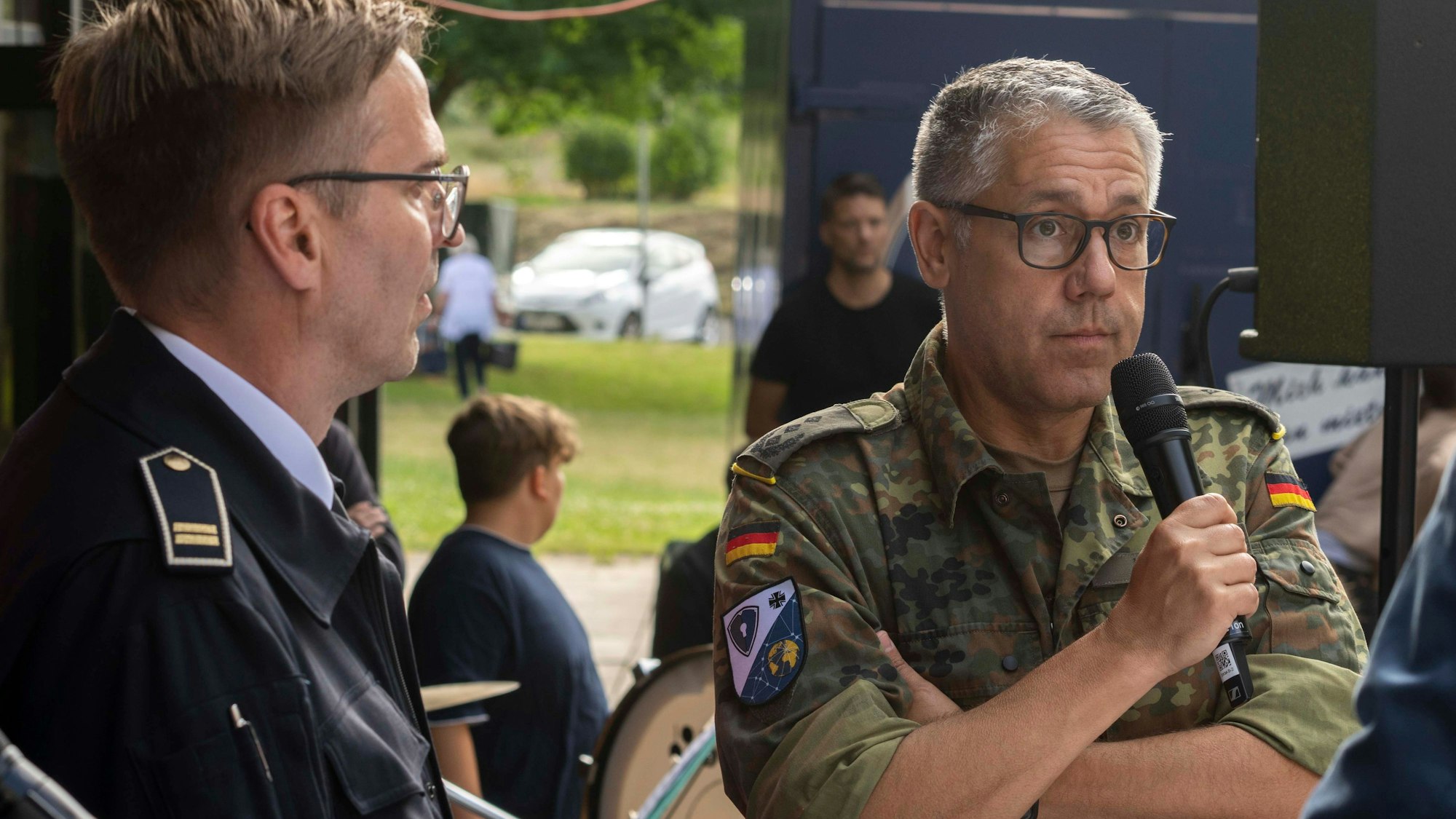 Zwei Männer stehen nebeneinander: Martin Fehrmann trägt eine Uniformjacke der Feuerwehr, Oberst Andreas Kubitz einen Flecktarnanzug der Bundeswehr.