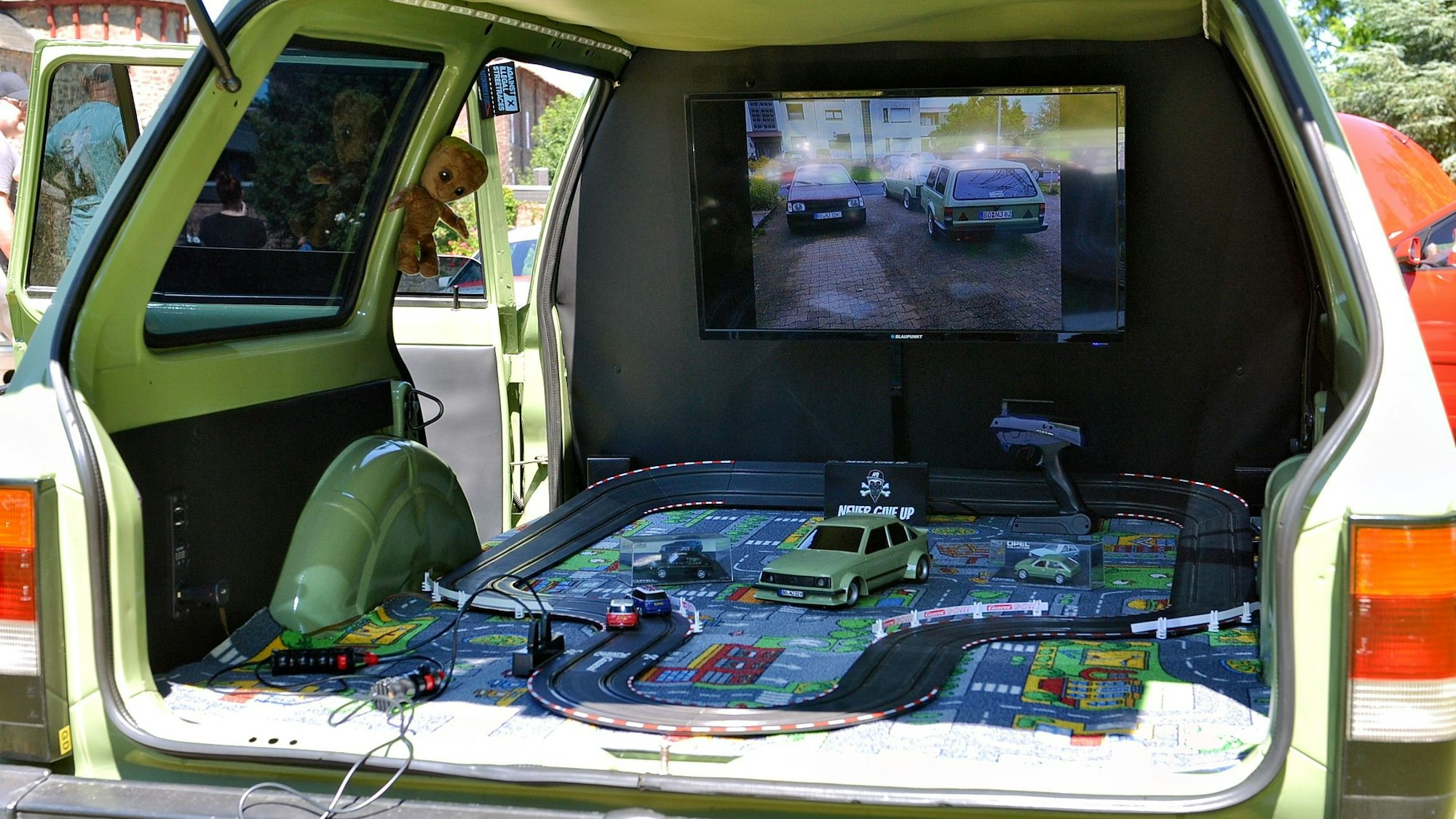 Das Heck eines Kadett Caravan wurde zu einem Anhänger umgebaut. Darin befindet sich eine Carrerabahn.