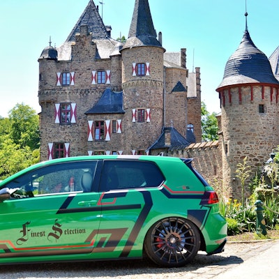 Ein grüner Tuning-Golf steht vor der Burg Satzvey