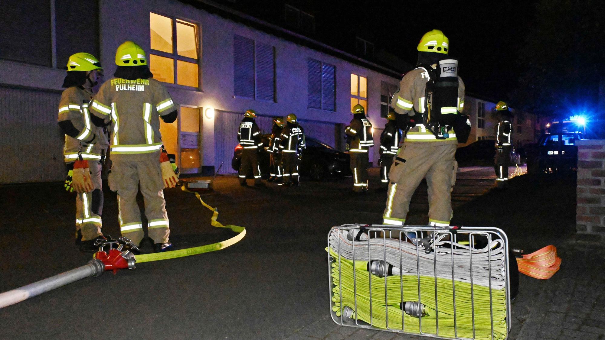 Auf dem Bild sind mehrere Feuerwehrleute bei einem nächtlichen Einsatz und ihre Ausrüstung zu sehen.