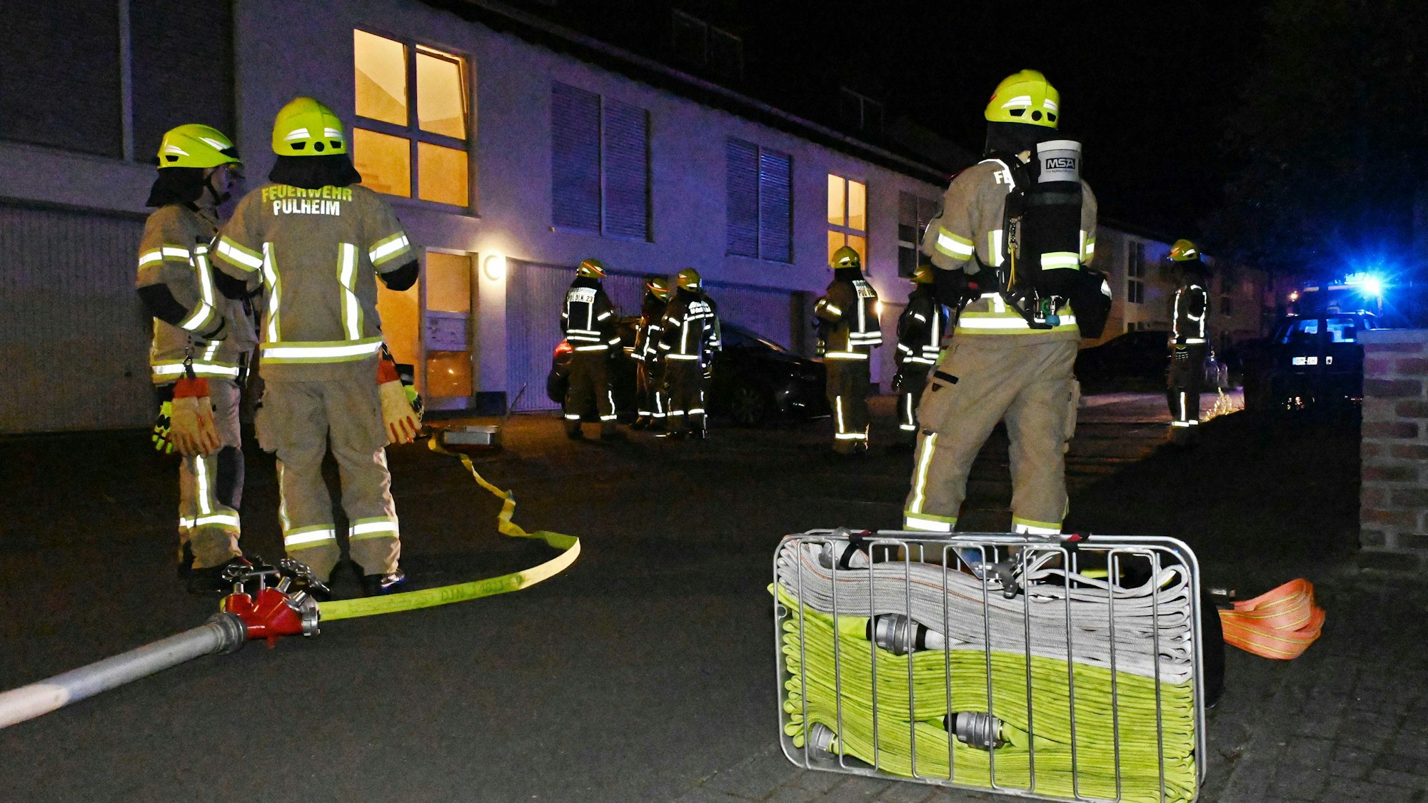 Auf dem Bild sind mehrere Feuerwehrleute bei einem nächtlichen Einsatz und ihre Ausrüstung zu sehen.